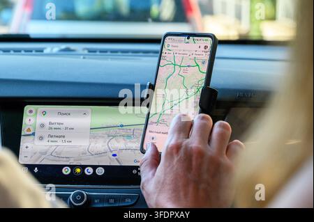 Iserlohn, Germany - August 13, 2026: Person's hand using smartphone with navigation app mounted inside a car. Stock Photo