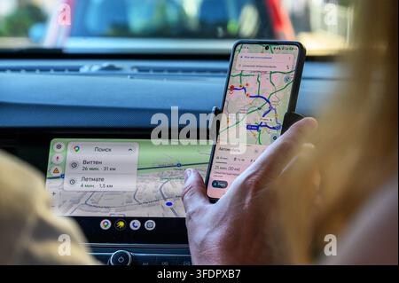 Iserlohn, Germany - August 13, 2026: Person's hand holding smartphone displaying navigation app inside a car. Stock Photo