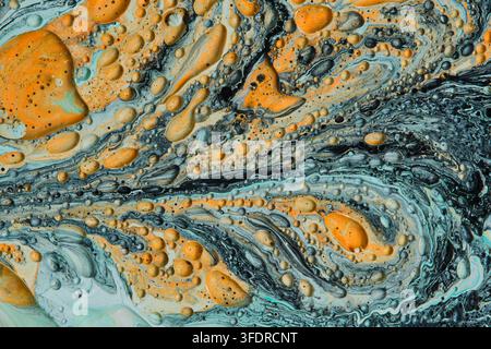 Abstract fluid art background with rich yellow bubbles floating on dark teal and grey marble waves Stock Photo