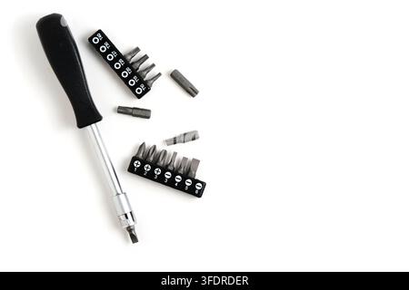 Screwdriver with bit holders and loose steel bits arranged on white background with copy space Stock Photo