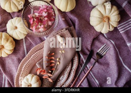 A warm and inviting fall tablescape featuring white pumpkins, decorative plates, soft napkins, and a glass goblet on a textured tablecloth, ideal for Stock Photo