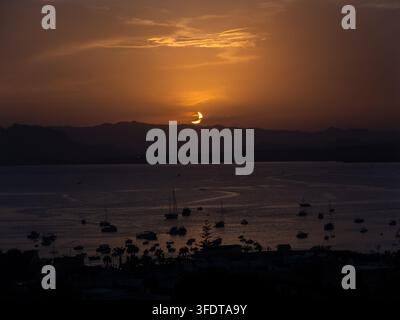 Partial Solar Eclipse During Sunset Over a Harbor with Boats, Spain Stock Photo