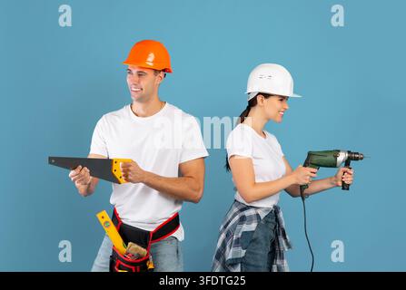 Young Couple In Hardhats Having Fun With Construction Tools During Repair Stock Photo