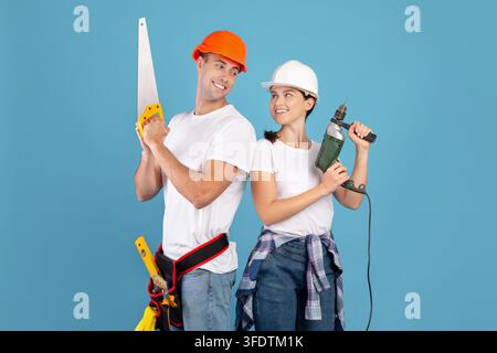 Ready For Repair. Smiling Couple In Protective Helmets Posing With Building Tools Stock Photo