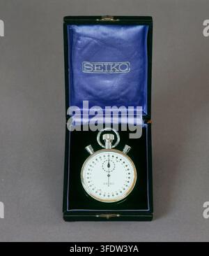 A silver Seiko stopwatch with a white dial and black markings, placed inside an open black box lined with blue fabric, dating from between 1890 and 2009. Stock Photo