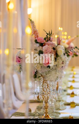 A long table is set for an event with bright flowers in vases and glowing candles. This arrangement suggests a festive gathering filled with joy and w Stock Photo