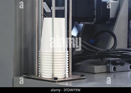 White paper coffee cups stand in a stack near  coffee machine on bar counter. Stock Photo