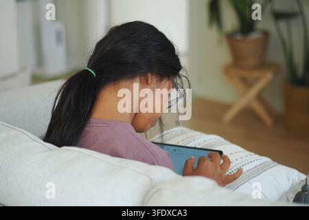 Girl using tablet while sitting on couch Stock Photo