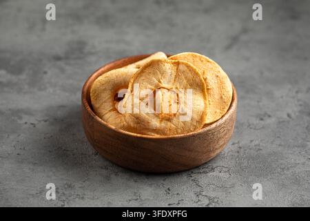Dried apple rings in wooden bowl on grey backdrop Stock Photo