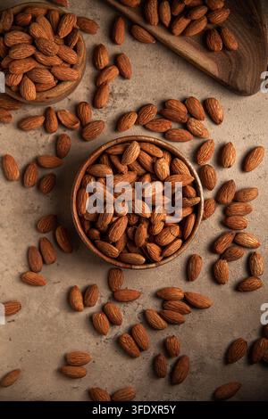 Raw almonds in wooden bowl on stone surface Stock Photo