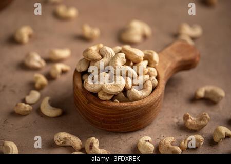 Cashew nuts in wooden scoop on stone surface Stock Photo
