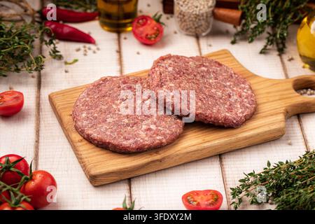 Raw burger patties on wooden cutting board Stock Photo