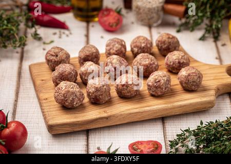 Raw meat meatballs on wooden cutting board Stock Photo