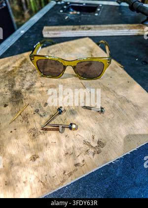 Close-up shot of yellow-framed sunglasses with brown lenses. Worn wooden board shows signs of use and age Stock Photo