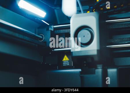 Working on 3D printer with laptop while preparing to print a project in a home office setting during daytime Stock Photo