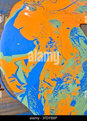 Abstract colorful paint swirls on curved surface. Bright orange, blue, and green blend dynamically Stock Photo