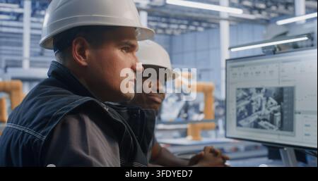 Engineering Specialists Collaborate Beside Automated Production Line, Analyzing Machine Data and Adjusting Control Parameters to Improve Efficiency, and Workflow Performance in Smart Manufacturing. Stock Photo