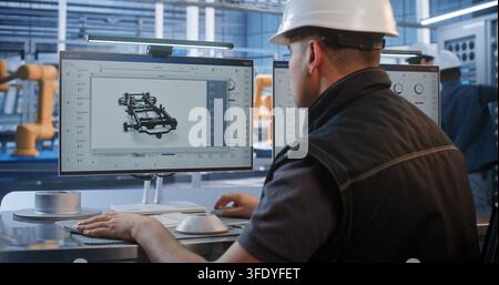 In Modern Smart Factory, Professional Male Engineer Uses Vernier Caliper to Measure Metal Prototype Near 3D CAD Chassis on Screen. Quality Control and Precision Engineering Optimize Industry 4.0. Stock Photo