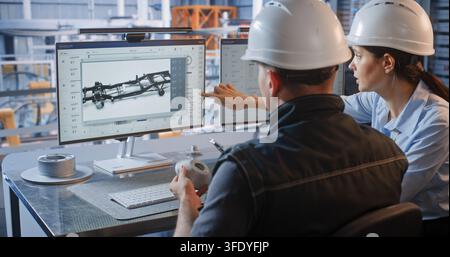 Female Engineer Points at 3D Car Chassis Screen while Discussing Component Design with Colleague Holding Prototype. Teamwork, CAD Software Drive Industry 4.0 Production Efficiency. Team Collaboration. Stock Photo