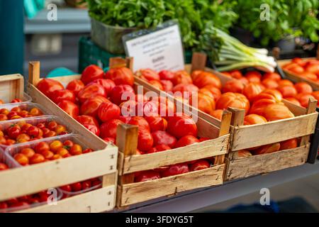 Fresh Red Tomatoes in Wooden Crates at Produce Market. Fresh red tomatoes displayed in wooden crates at an outdoor produce market. Stock Photo