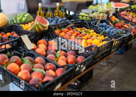 Colorful Fresh Fruit Display at Outdoor Produce Market. Fresh peaches, apricots, plums, and watermelon displayed in crates at an outdoor produce Stock Photo