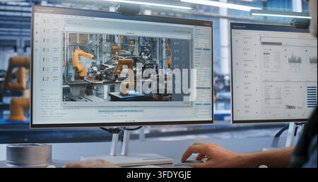 Close Up of Male Specialist Watching Live Video Stream of Robotic Arms Assembling Car Body on Computer Display. Smart Factory Automation and Digital Twin Monitoring Optimize Production Lines. Stock Photo