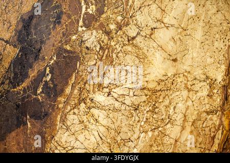 Natural Brown and Beige Marble Stone Texture. Close-up of brown and beige natural stone with intricate veins, cracks, and mineral patterns. Stock Photo