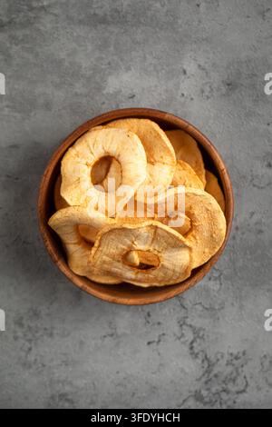 Dried apple rings in wooden bowl on grey backdrop Stock Photo