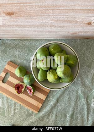 Fresh ripe figs and sliced figs arranged in bowls on a rustic wooden table. Stock Photo