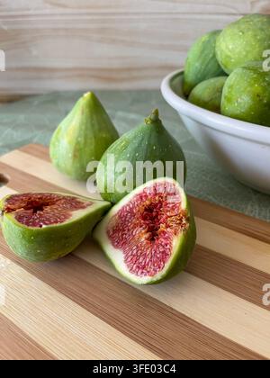 Fresh ripe figs and sliced figs arranged in bowls on a rustic wooden table. Stock Photo