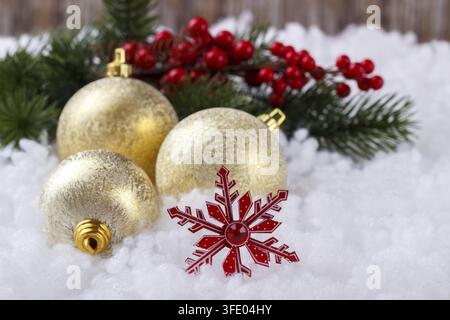 Christmas decoration with golden balls and red snow flakes on white snow background, selective focus Stock Photo