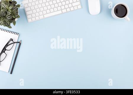 Modern office blue desk table notepad pen plant keyboard mouse glasses top view copy space Stock Photo