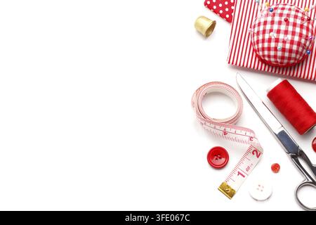 Sewing items pillow with needles, red buttons and fabric, scissors, thimble, thread, measuring tape isolated over white, copy space Stock Photo