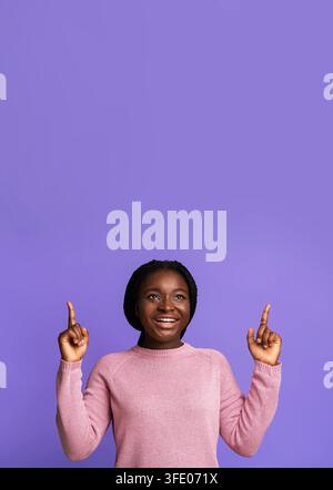 Look There. Cheerful Black Young Woman Pointing Up At Copy Space Stock Photo