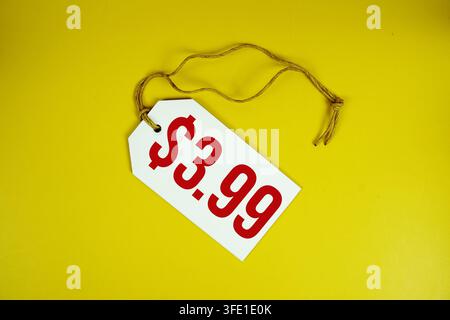 Price tag with "$3.99" is placed on yellow background Stock Photo