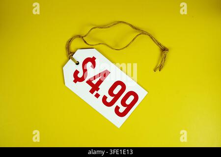 Price tag with "$4.99" is placed on yellow background Stock Photo