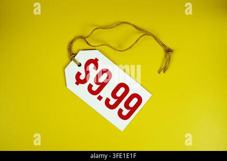 Price tag with "$9.99" is placed on yellow background Stock Photo