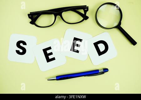 SEED alphabet letters with magnifying glass, eye glasses and pen on yellow background Stock Photo
