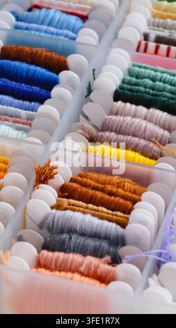 Close-up shot of a plastic box filled with colorful embroidery floss wound onto bobbins Stock Photo