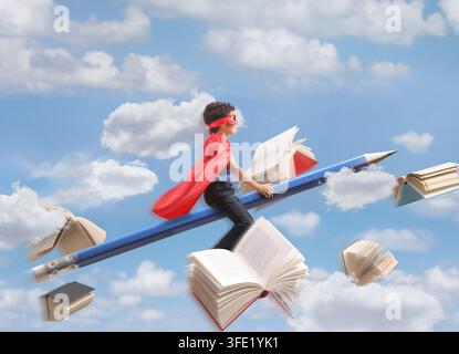 Kid in a superhero costume flying on a big pencil in the sky Stock Photo