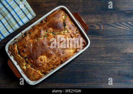 Homemade golden baked pie in ceramic dish on wooden background, close up, copy space. Top view of freshly baked savory pie with golden brown crust in Stock Photo