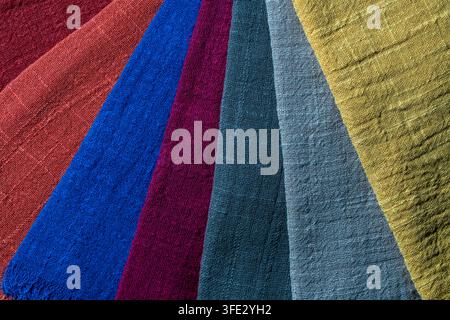 Colorful cotton fabric swatches arranged in fan shape top view. Close up of multi colored textured linen napkins laid out as color palette fan showing Stock Photo