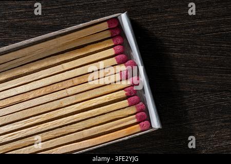 Wooden matches with red heads aligned in an open matchbox. Close up top view of unused safety wooden matches neatly arranged inside cardboard box on d Stock Photo