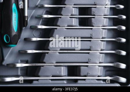 Flat lay chrome spanners and screwdriver set neatly placed in slots gray organizer Stock Photo