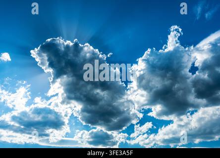 Sun rays breaking through clouds in blue sky Stock Photo