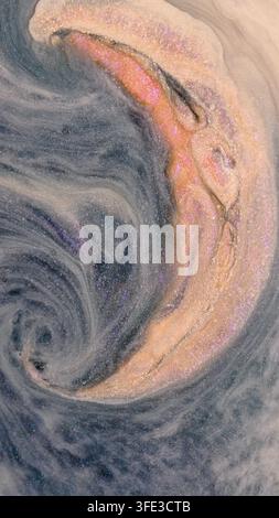 Alcohol ink is mixed on a flat surface, creating colorful swirls and patterns. The blending shows a range of colors including pink, blue, and gold, wi Stock Photo