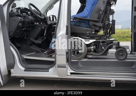 A man using a wheelchair is boarding a modified vehicle designed for personal mobility. This scene takes place in an open area. Stock Photo