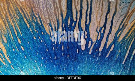 The image shows close-up details of alcohol ink being mixed. Different colors blend together, creating vibrant swirls and patterns on the surface. Thi Stock Photo
