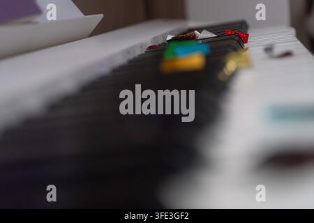 Creative close-up of colorful confetti and small party decorations scattered across piano keys. Selective focus creates an abstract festive music back Stock Photo