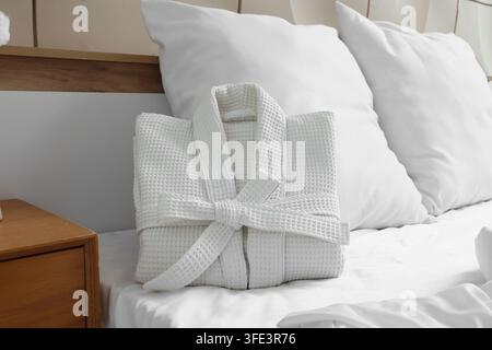 Folded waffle bathrobe on bed in room Stock Photo